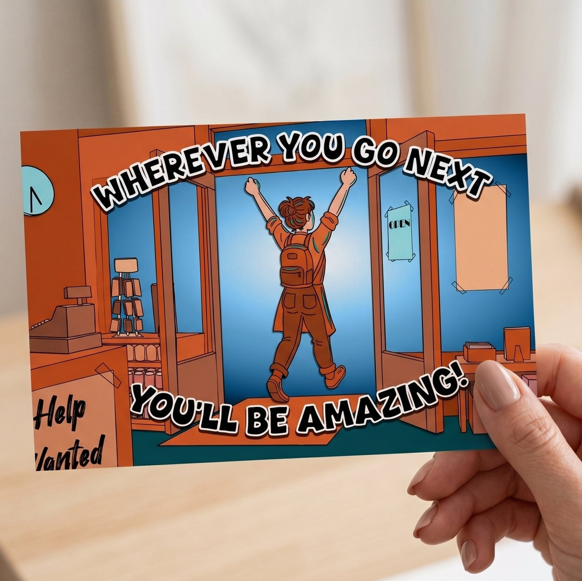 Product image of a hand holding a greetings card. On the card an exuberant shop worker is walking out of the front door. The text reads 'wherever you go next, you'll be amazing!'