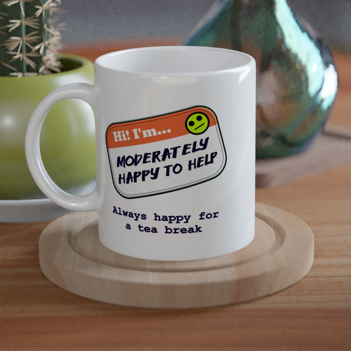 product image of a white mug with an image of an orange nametag saying 'hi, i'm moderately happy to help. Always happy for a tea break.'