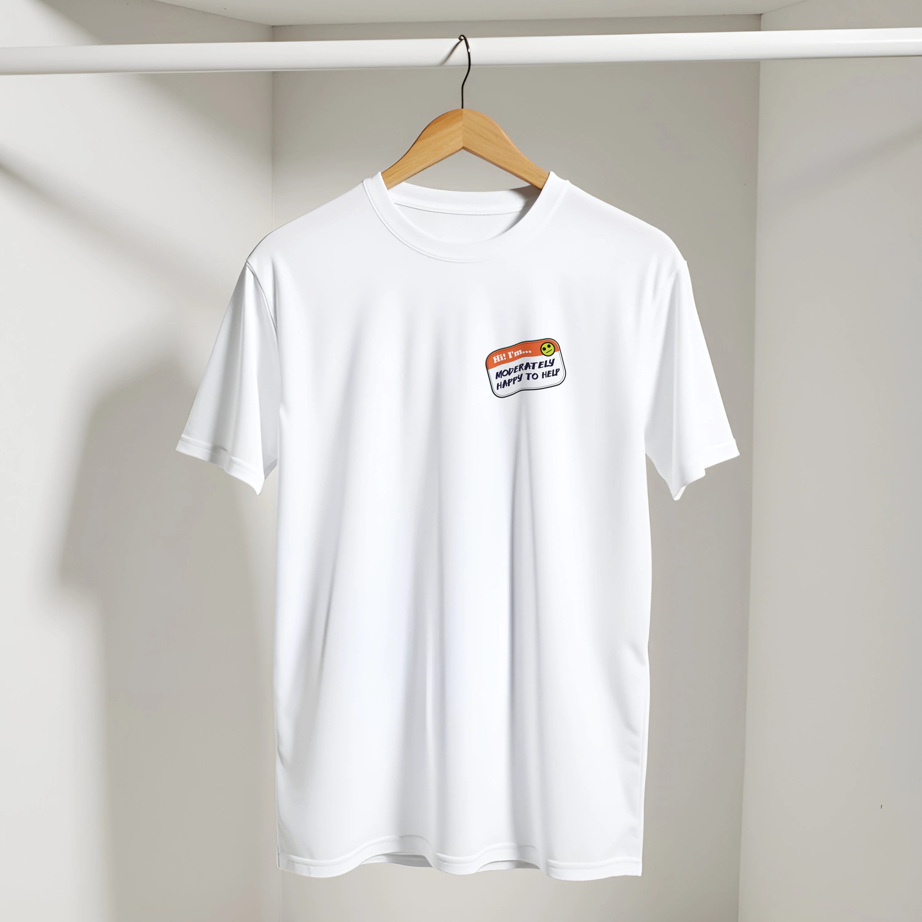 Image of a white t-shirt on a hanger with a printed imitation nametag saying 'Hi! I'm Moderately Here to Help' by Retailer Therapy