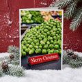 image of a greetings card in a christmassy scene. the card depicts a mound of brussel sprouts on a supermarket checkout. the divider says 'merry christmas'